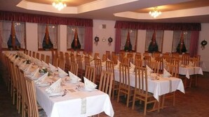 A banquet hall with long tables set for a formal event, wooden chairs, and decorative wreaths on the walls. - Baringer Hof (Neuburg)