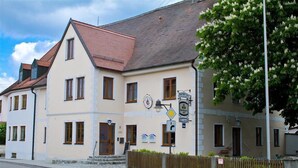 A two-story building with a beige facade, multiple windows, and a red-tiled roof. - Baringer Hof (Neuburg)