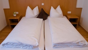 A double bed with a wooden headboard, two bedside tables, and a small vase on one table. - Baringer Hof (Neuburg)