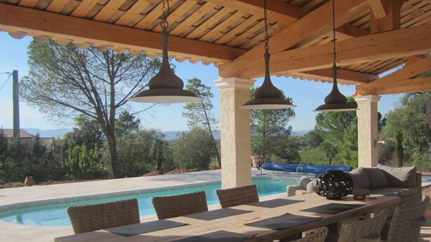 An outdoor pool area with a wooden pergola, wicker furniture, and hanging pendant lights. - In peace and quiet: villa with AC, pool, 300 m² terraces in nature reserve (Vidauban)