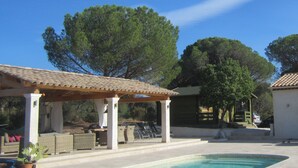 A pool area with a pergola, lounge chairs, and a covered seating area. - In peace and quiet: villa with AC, pool, 300 m² terraces in nature reserve (Vidauban)