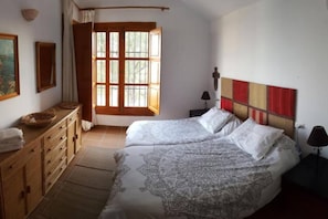 A bedroom with two beds, a wooden dresser, a window with curtains, and a wall-mounted lamp. - Charming Villa with the best Panoramic views (Nerja)