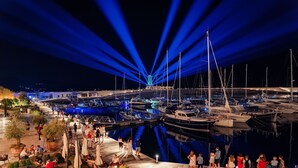 Una marina de nit amb vaixells amarrats, un passadís cobert i zones d'seients exteriors.