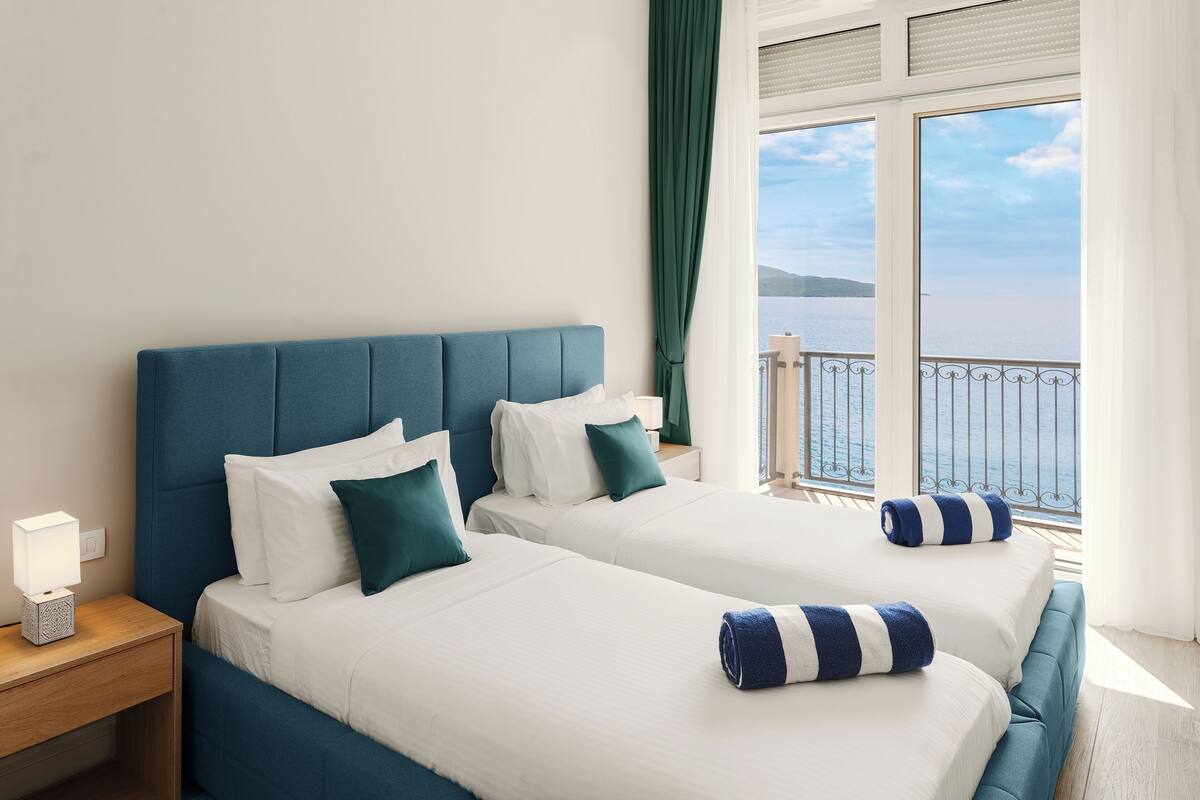Ein Hotelzimmer mit zwei Betten, einem Nachttisch und Meerblick.
