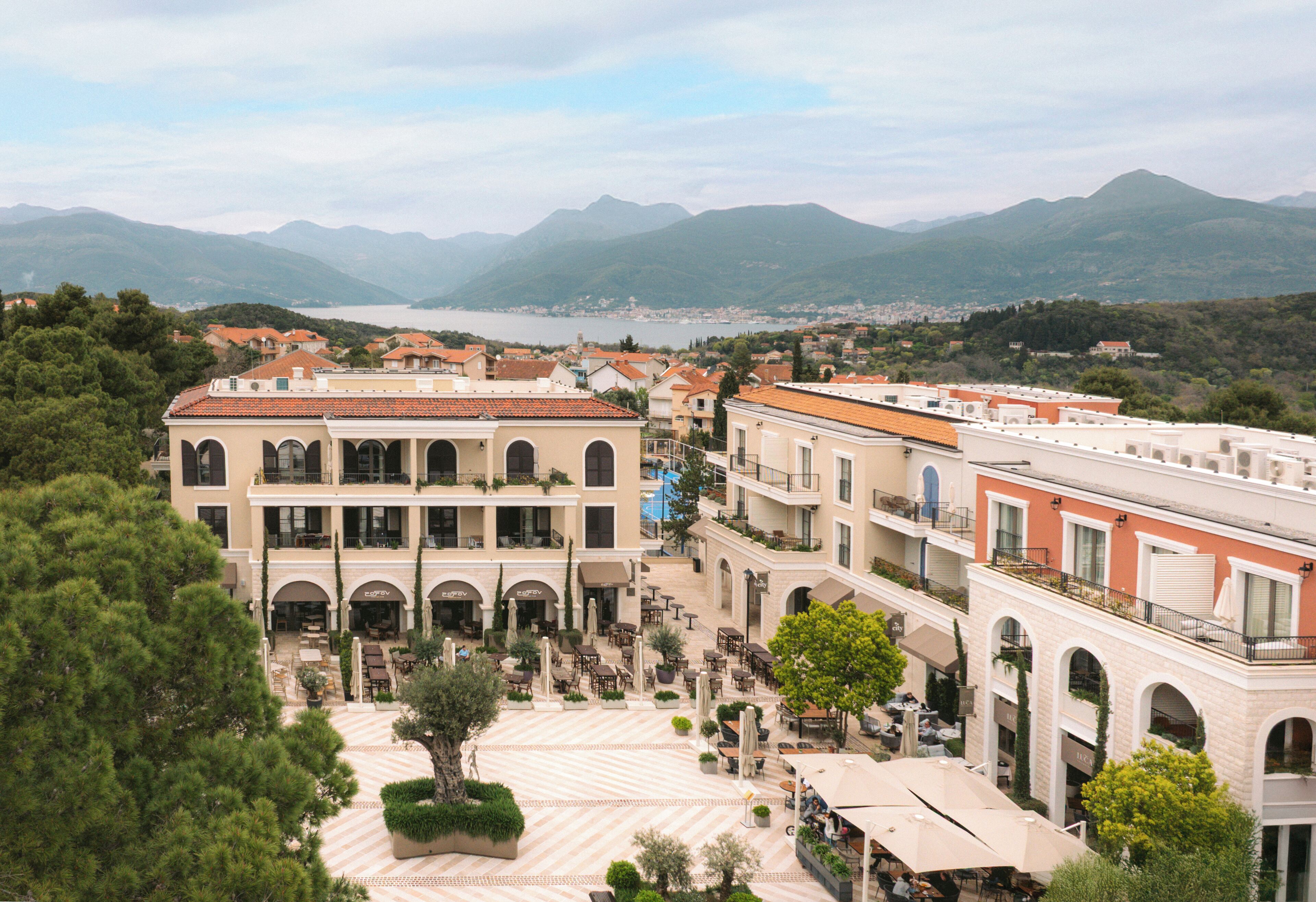 Un hotel con varios pisos, zonas de estar al aire libre y vistas a montañas y un lago.