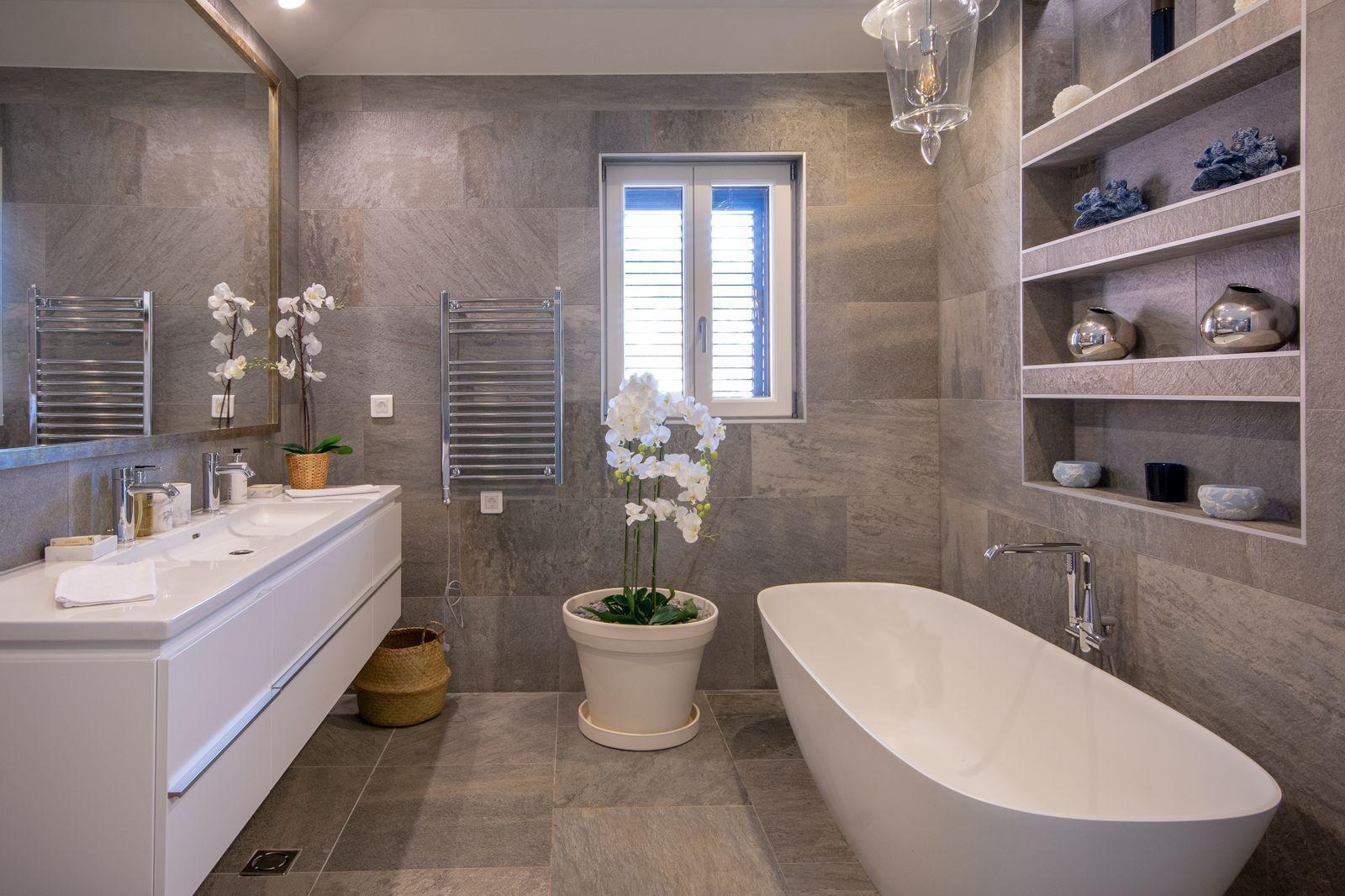 Un baño moderno con una bañera independiente, un tocador doble y un espejo grande.