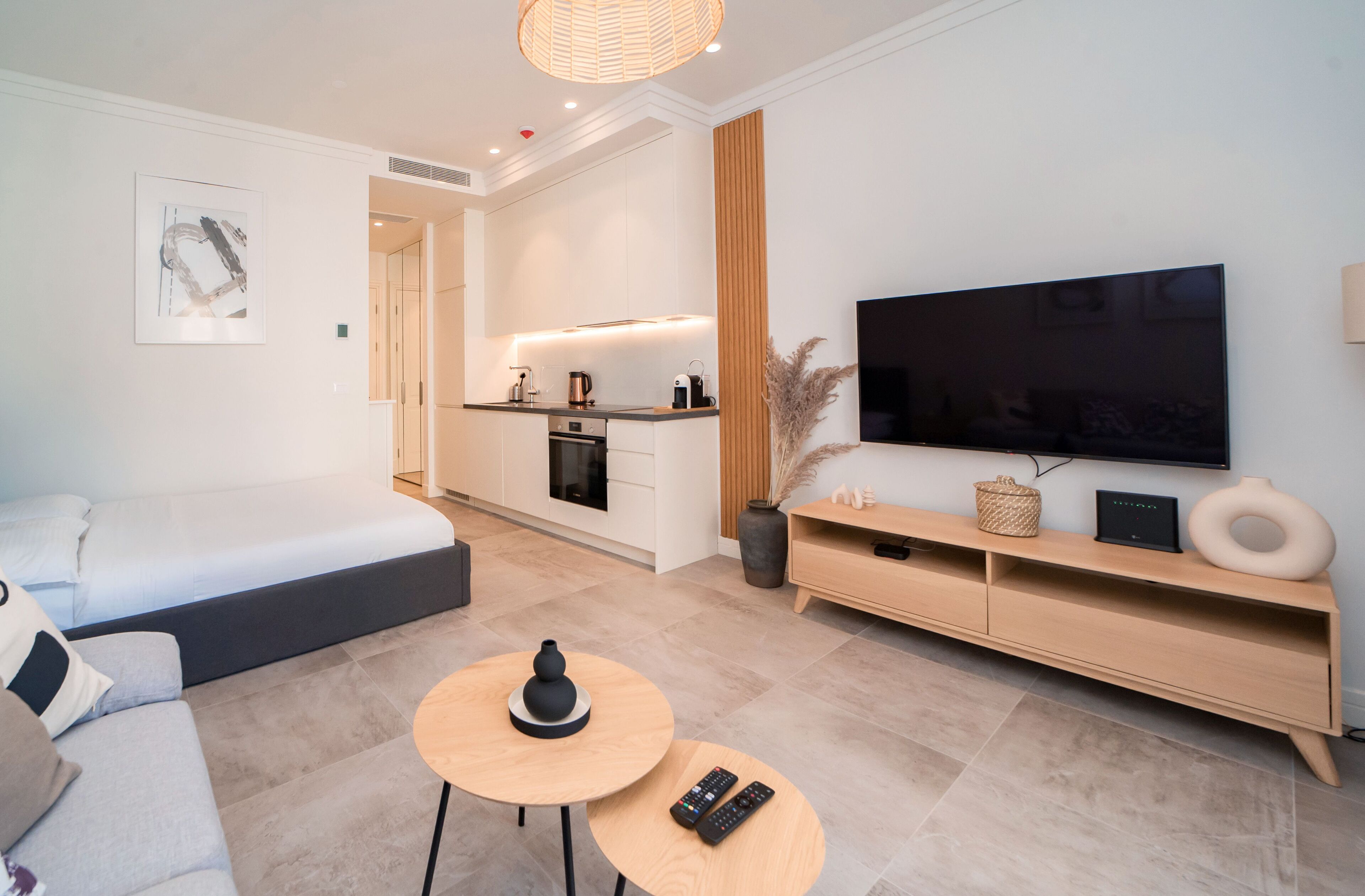 A modern living room with a sofa, a coffee table, a TV, and a kitchen area in the background.