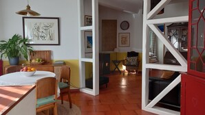 Une pièce comprenant une table à manger, des chaises, une plante en pot et un meuble rouge.