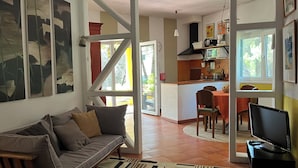 Un salon comprenant un canapé, un téléviseur et un coin repas avec une table et des chaises.
