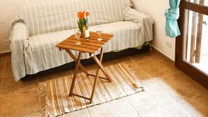 Un salon chaleureux avec un canapé à rayures, une table basse en bois ornée d’un vase de fleurs et un petit panier fixé au mur.