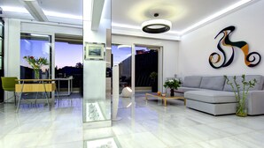 A modern living room with a grey sofa, a coffee table, and a dining area with a table and chairs. - Frixos Acropolis luxury apartment (Athens)