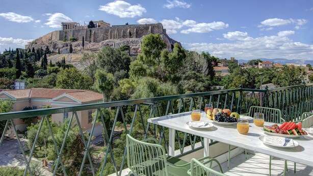 A terrace with a table set for breakfast, overlooking ancient ruins and a mountainous landscape. - Frixos Acropolis luxury apartment (Athens)