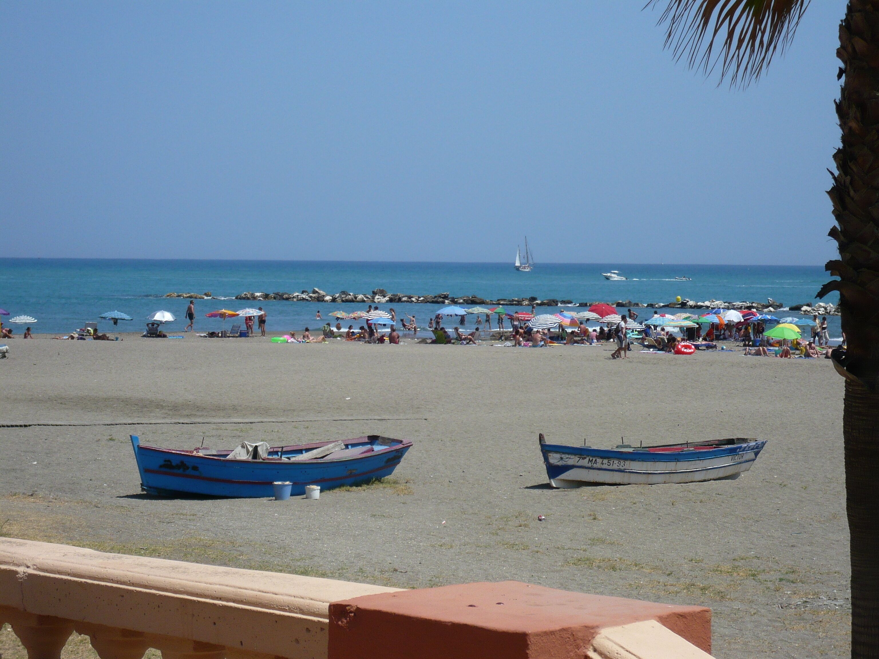 Een strand met boten en parasols.
