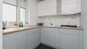 Una cocina moderna con armarios blancos, una estufa negra y un ventanal con persianas.