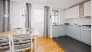 Una cocina moderna con gabinetes grises, una mesa de comedor de madera y luces colgantes.