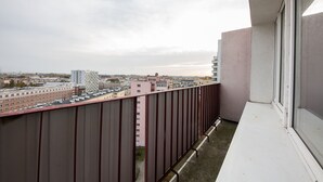 Un balcón con vista a un paisaje urbano, que incluye edificios y un cielo nublado.