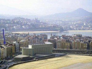A coastal cityscape with a prominent modern building, a wide sandy beach, and a mountain in the background. - ZURRIOLA SURF BEACH. Optional parking. ESS00856 (Donostia)