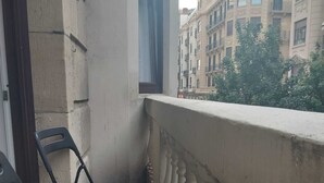 Een balkon met twee zwarte stoelen, uitzicht op gebouwen en een decoratieve balustrade.
