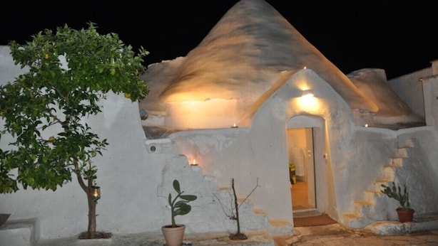 A traditional white-roofed building with a small entrance and a tree in the foreground. - Raffinata dimora tipica tra ulivi, mandorli e fichi d'india (Ostuni)