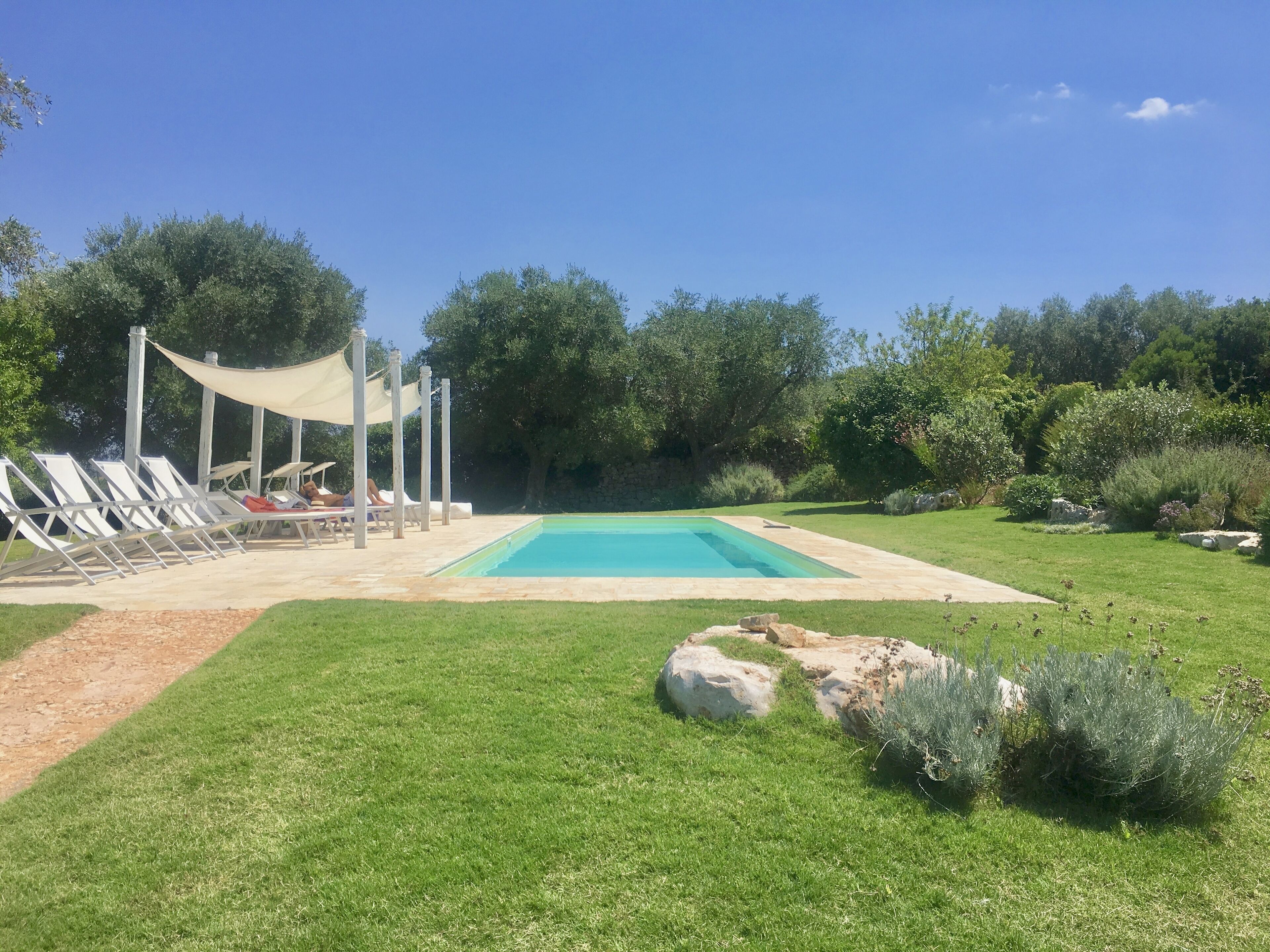 A swimming pool with lounge chairs and a shaded area.
