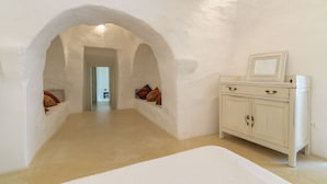 A room with white walls, a white cabinet, and a bed. There are two archways leading to another room. - Raffinata dimora tipica tra ulivi, mandorli e fichi d'india (Ostuni)