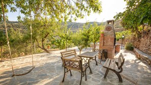 Un patio al aire libre con suelo de piedra, bancos de madera y una mesa.