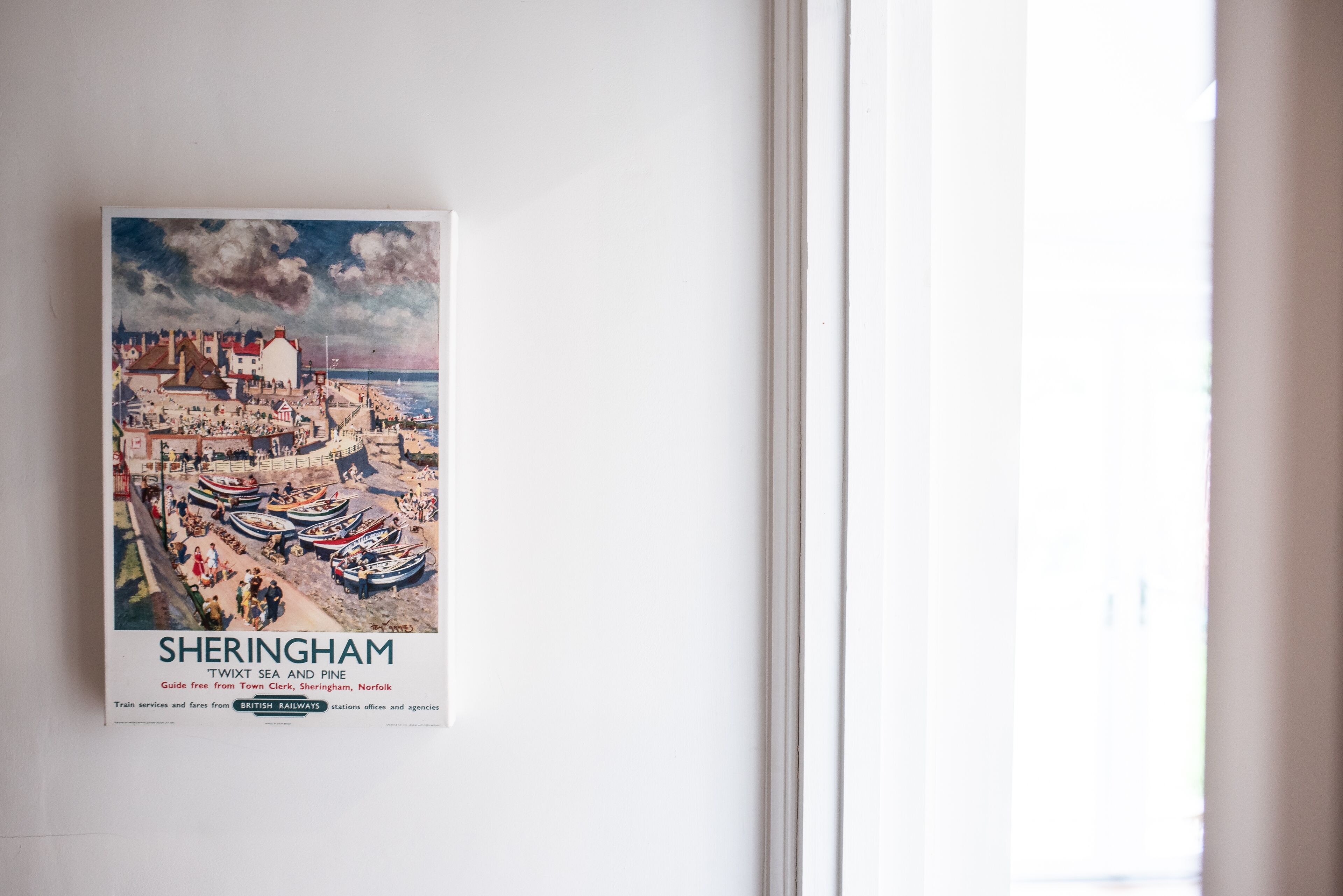 A poster of Sheringham with a coastal scene, including boats and buildings.