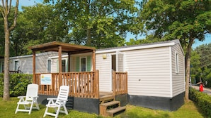 A mobile home with a porch, two white lawn chairs, and a 'Happy Premium' sign. - Happy Camp in Camping Iscrixedda (Lotzorai)