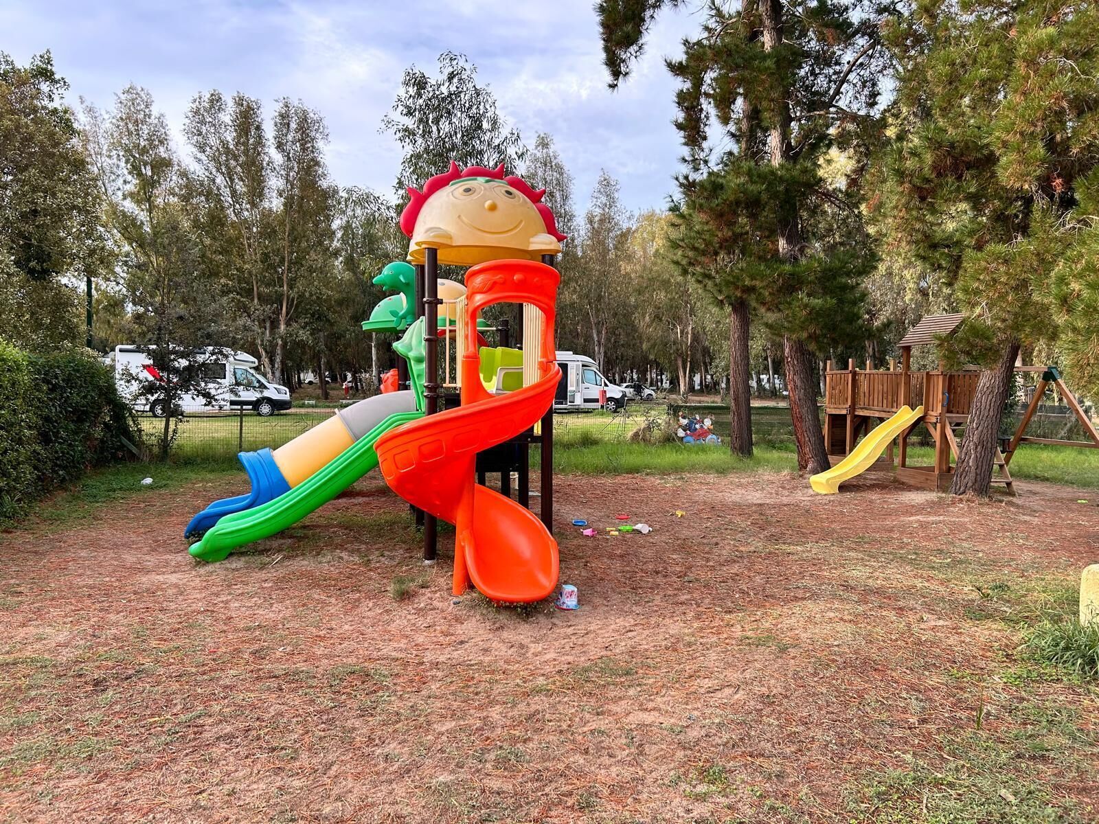 A playground with a slide, climbing structures, and a wooden playhouse.