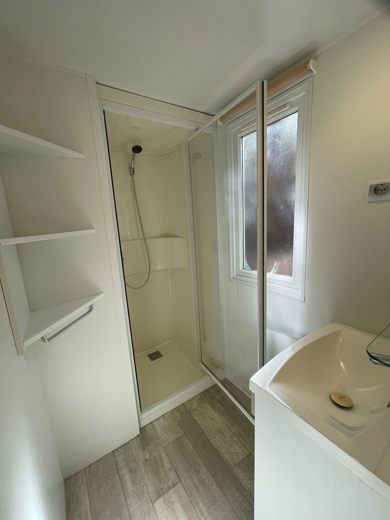 A bathroom with a shower, a sink, and a window.