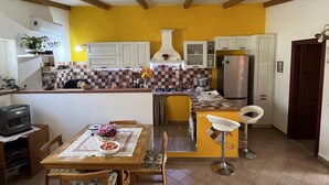 Una cocina con una isla central, vigas de madera, salpicadero de azulejos y un comedor con mesa y sillas.
