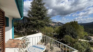Un balcón con mesa y silla, con vista a un paisaje montañoso.