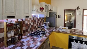 Una cocina con salpicadero de baldosas a cuadros, armarios de madera, un refrigerador de acero inoxidable y una estufa a gas.