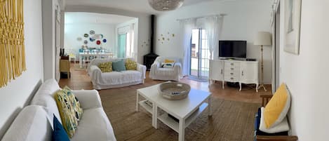 A spacious living room with a white sofa, a white coffee table, and a television on a cabinet.