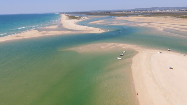 An aerial view of a beach with clear waters, a sandy shore, and boats. - Comfortable, cozy and comfy apartment by the Ria Formosa (Olhão)