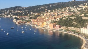 Un poble costaner amb una platja, barques i edificis al passeig marítim.