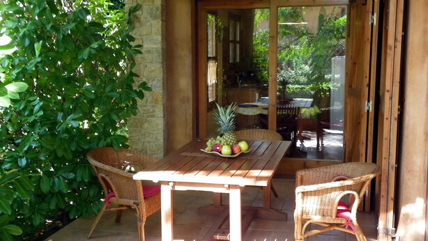 An outdoor patio with a wooden table and wicker chairs, surrounded by greenery. - House with garden and terrace, ideal to relax, near the Costa Brava (Monells)
