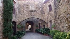 A narrow stone corridor with arched passageways, potted plants, and a rustic stone building. - House with garden and terrace, ideal to relax, near the Costa Brava (Monells)