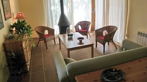 A cozy living room with wicker furniture, a fireplace, and a view of the outdoors. - House with garden and terrace, ideal to relax, near the Costa Brava (Monells)