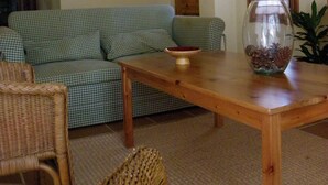 A cozy living room with a checkered sofa, a wooden table, wicker chairs, and a decorative fishbowl. - House with garden and terrace, ideal to relax, near the Costa Brava (Monells)