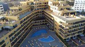 Un hôtel à plusieurs étages doté d’une cour intérieure avec une piscine et des chaises longues.