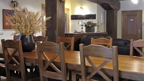 A dining area with a wooden table and chairs, a potted plant, and a kitchen in the background. - Casa Martikonea for 16 people (Basaburua)