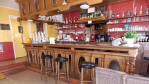 Eine Bar mit Holzhockern, Regalen voller Flaschen und einer Theke.