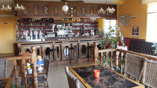 Ein Restaurantinneres mit Holzbalken und Sitzbereich, inklusive Tische und Stühle.