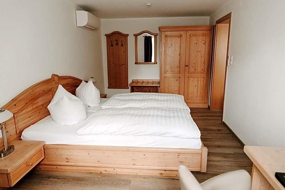 Un dormitorio con una cama de madera, una mesita de noche, un armario y un espejo.