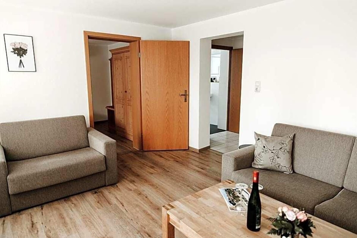 Un salon avec deux canapés, une table basse en bois et une porte donnant sur une autre pièce.