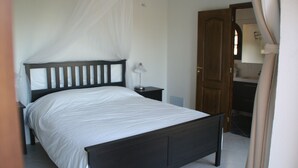 Quarto com cama, mesa de cabeceira e criado-mudo.