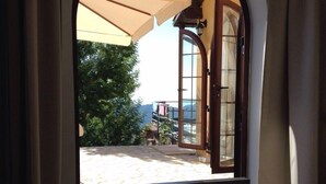 Cama com bandeja de itens de café da manhã e vista para um pátio com mesa e cadeiras.