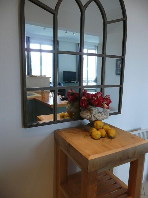 A wooden console table with a mirror above it, reflecting a room with a television and a window.