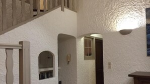 Eine Treppe führt zu einer Empfangsebene mit einer weißen, strukturierten Wand und einem Holztisch.